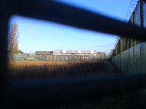 A tarpaulin covers the fire-damaged roof of 'Blue Block' at Campsfield - Photo by Corporate Watch 30.11.13
