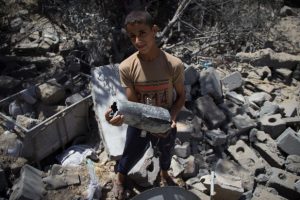A Palestinian youth holds part of a missle launched by an Israeli drone which killed a family in the Zeitoun neighborhood of Gaza City, 14 July. (Basel Yazouri / ActiveStills)