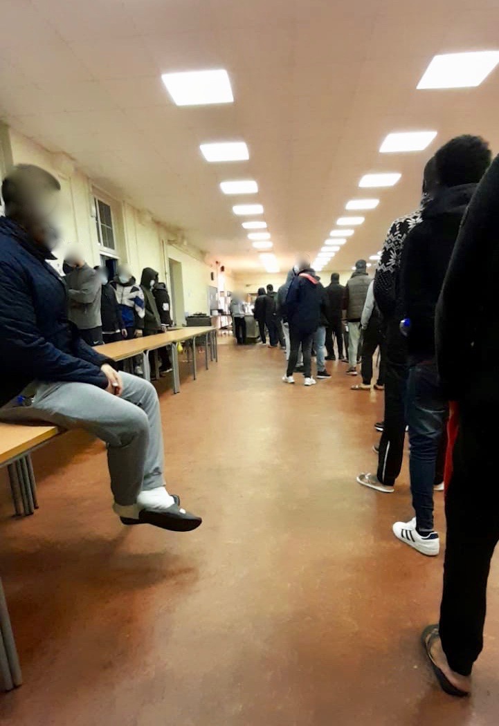 Image shows men in a queue close together with no social distancing 