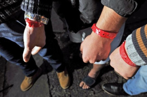 Image shows three people wearing red wrist bands